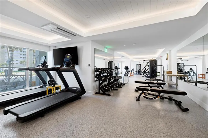 Gym with a tray ceiling and baseboards