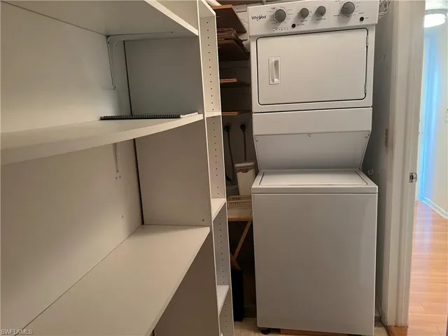 Washroom with light wood-type flooring and stacked washer / dryer