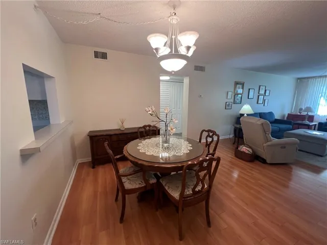 Dining space with wood-type flooring, a textured ceiling, and a chandelier