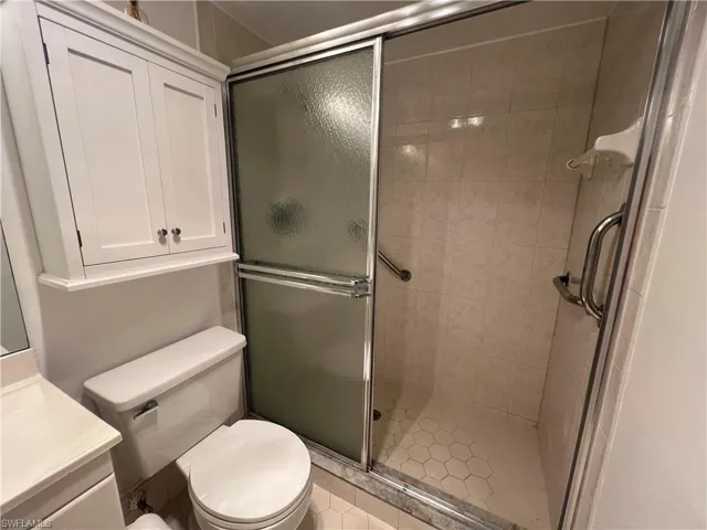 Primary Bathroom with vanity, tile patterned floors, toilet, and a shower with door