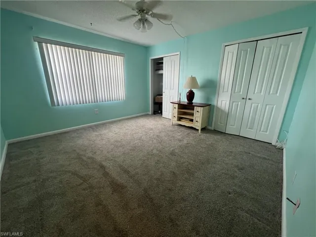 Guest bedroom with two large closets, carpet flooring & ceiling fan