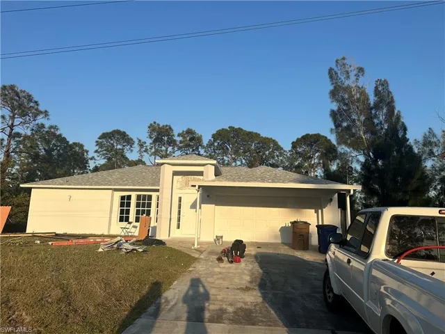 Single story home with a garage, a shingled roof, and driveway