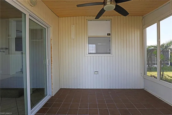 Unfurnished sunroom with wooden ceiling, tile patterned floors, and wooden walls