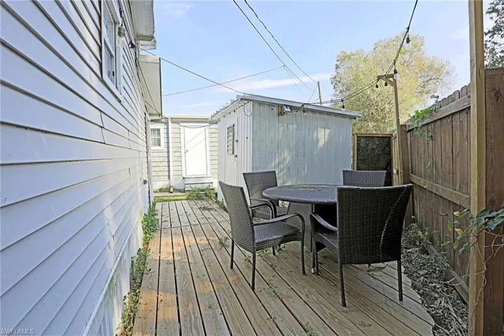 Wooden terrace featuring outdoor dining space, an outdoor structure, and a fenced backyard