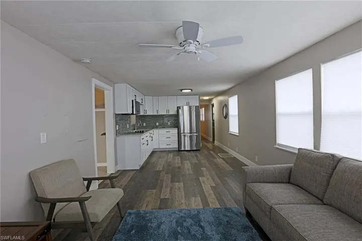 Living room featuring dark wood-style flooring and a ceiling fan