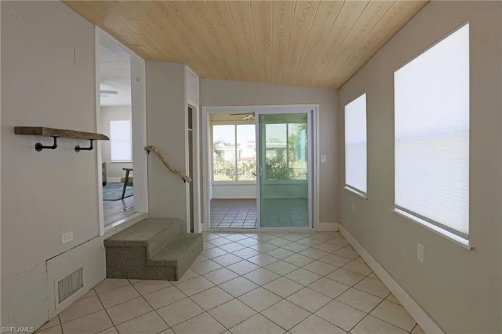 Doorway featuring wood ceiling, tile patterned flooring, vaulted ceiling, and stairway