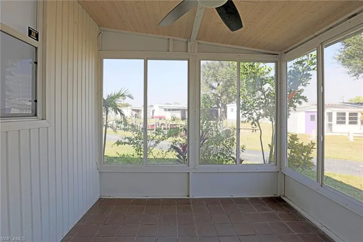 Unfurnished sunroom with a ceiling fan, plenty of natural light, and lofted ceiling