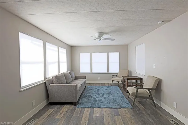 Living area with dark wood-style floors, a ceiling fan, and plenty of natural light