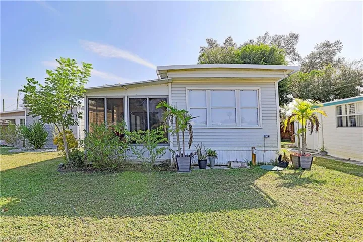 Rear view of property featuring a sunroom and a lawn