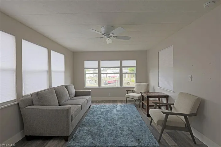 Living room with dark wood-style floors and a ceiling fan
