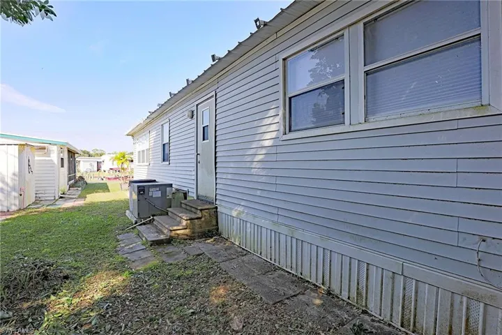 View of property exterior featuring a yard and entry steps