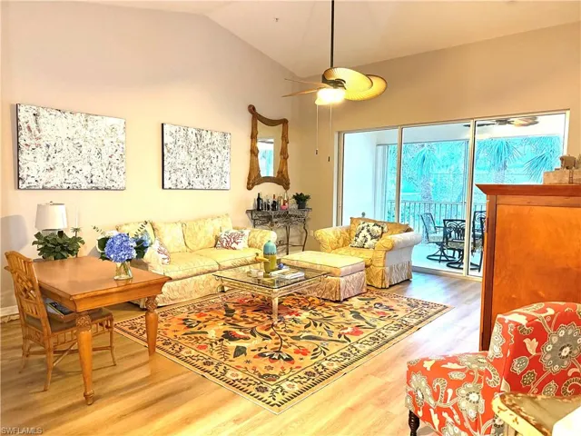 Living room featuring vaulted ceiling, light wood finished floors, and a ceiling fan
