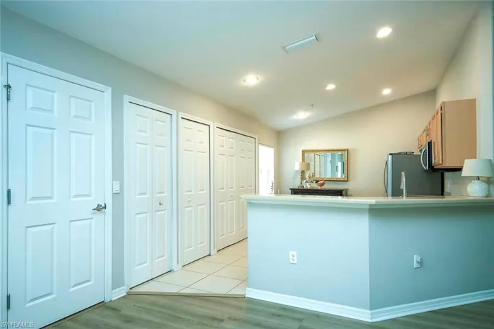 Kitchen with vaulted ceiling, light countertops, recessed lighting, light wood-type flooring, and a peninsula