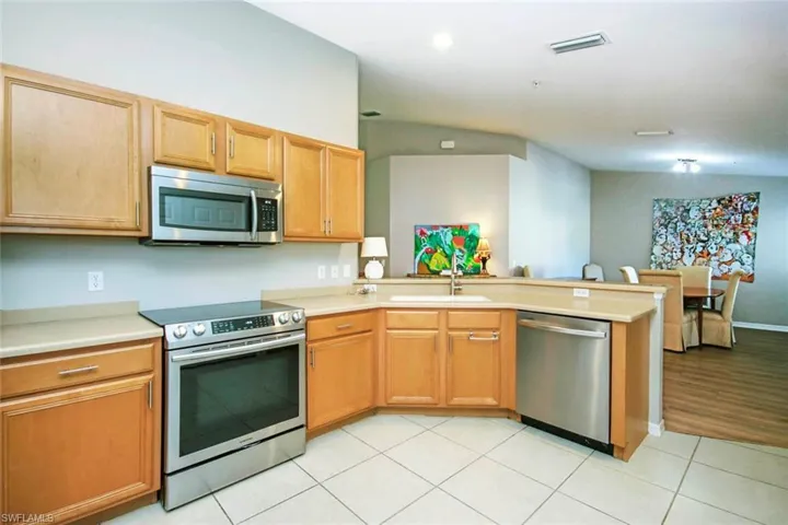 Kitchen featuring appliances with stainless steel finishes, a peninsula, and light tile patterned flooring