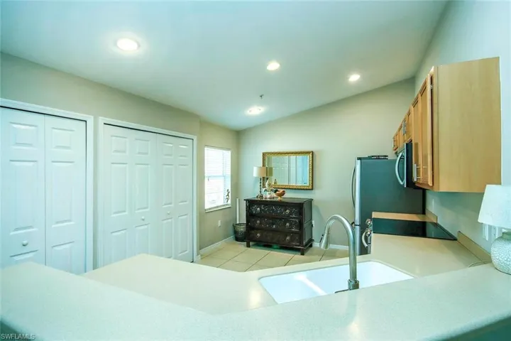 Kitchen with recessed lighting, lofted ceiling, stainless steel microwave, black electric range, and light tile patterned floors