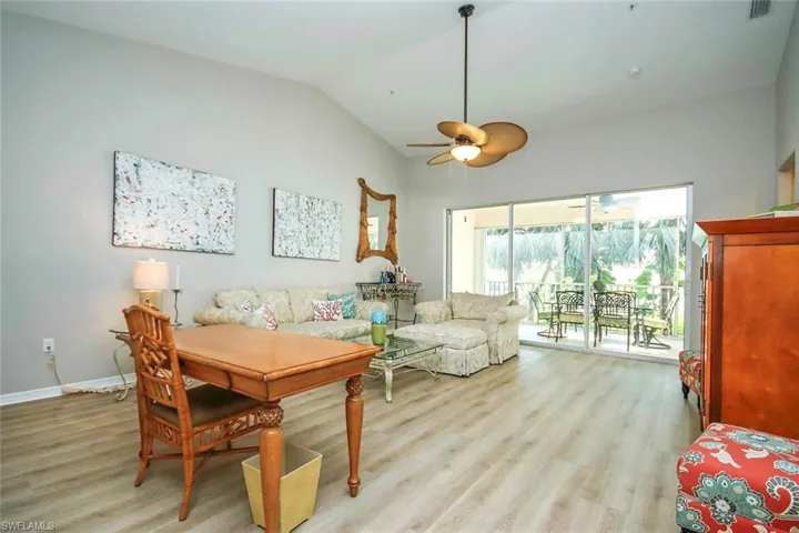 Living room featuring light wood-style floors, vaulted ceiling, and ceiling fan