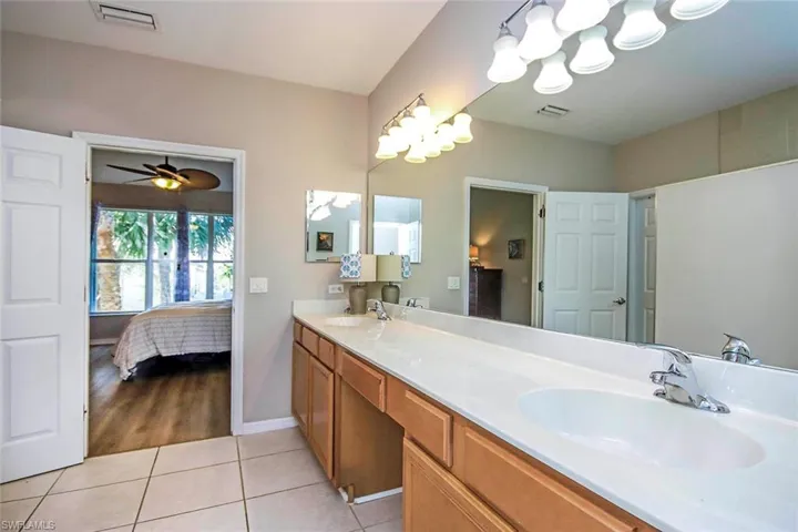 Full bathroom with double vanity, light tile patterned flooring, connected bathroom, and a ceiling fan
