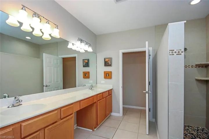 Bathroom with double vanity, light tile patterned floors, walk in shower, and recessed lighting