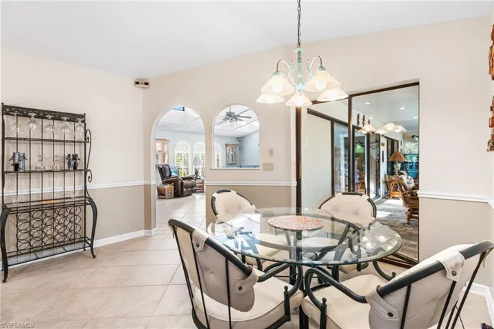 Dining space featuring baseboards, a notable chandelier, arched walkways, and light tile patterned floors