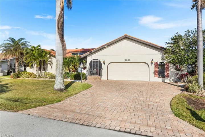 View of front facade featuring decorative driveway, stucco siding, an attached garage, and a front lawn