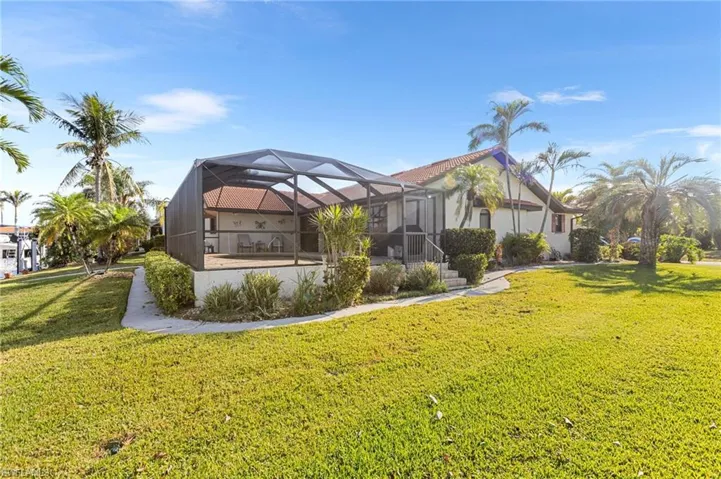 Back of property featuring stucco siding, a lanai, and a yard