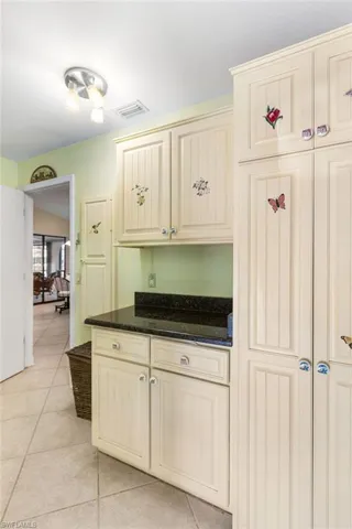 Kitchen with visible vents, cream cabinets, dark stone countertops, and light tile patterned floors