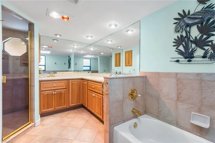 Bathroom with double vanity, a garden tub, tile patterned flooring, and a stall shower