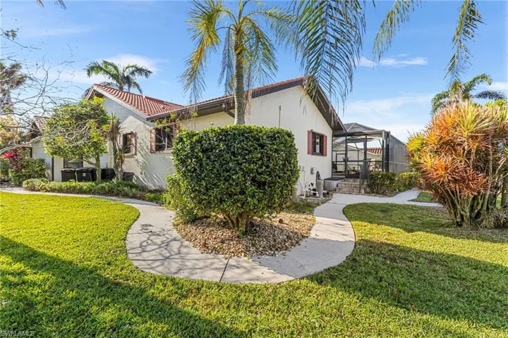 View of home's exterior with a tile roof, stucco siding, a lanai, and a yard