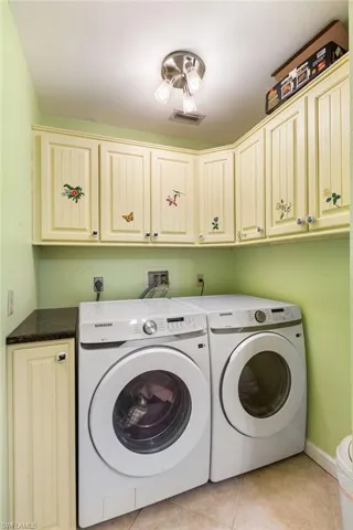 Washroom with visible vents, baseboards, cabinet space, separate washer and dryer, and light tile patterned floors