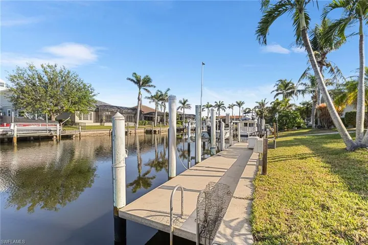 Dock area featuring a residential view, boat lift, a water view, and a lawn