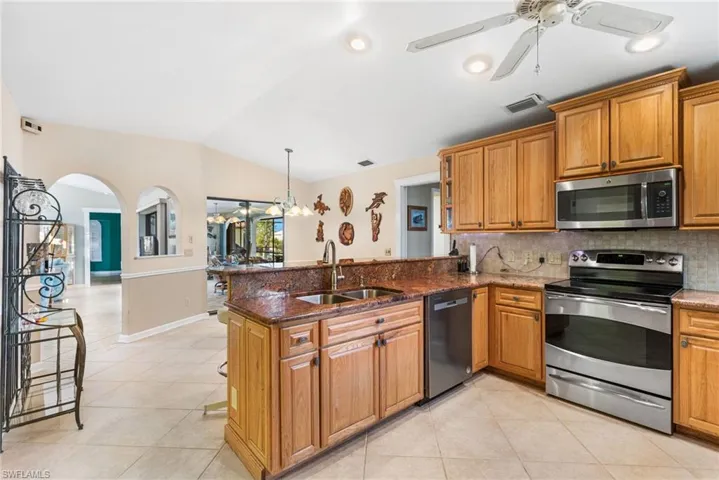 Kitchen with a sink, appliances with stainless steel finishes, a peninsula, visible vents, and ceiling fan