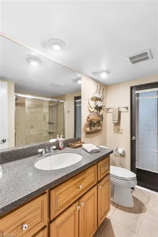 Bathroom with visible vents, toilet, tile patterned floors, vanity, and a stall shower