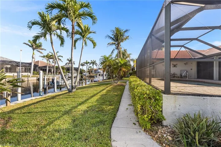 View of yard with a water view, boat lift, a lanai, an outdoor pool, and a boat dock