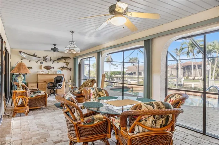 Sunroom featuring ceiling fan and brick floor