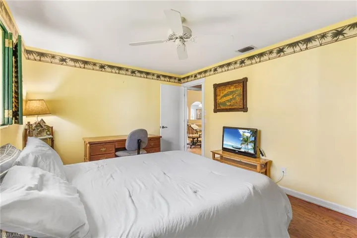 Bedroom with visible vents, baseboards, ceiling fan, wood finished floors, and arched walkways