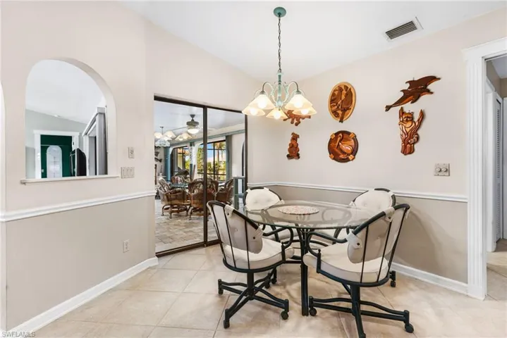 Dining room featuring light tile patterned flooring, visible vents, arched walkways, and vaulted ceiling