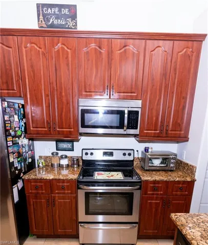 Kitchen with stone countertops, light tile patterned floors, and appliances with stainless steel finishes