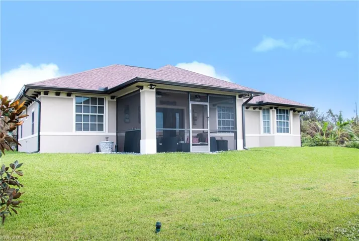 Back of house with a sunroom and a lawn