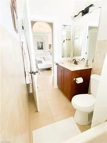 Bathroom featuring tile patterned floors, vanity, toilet, and tile walls