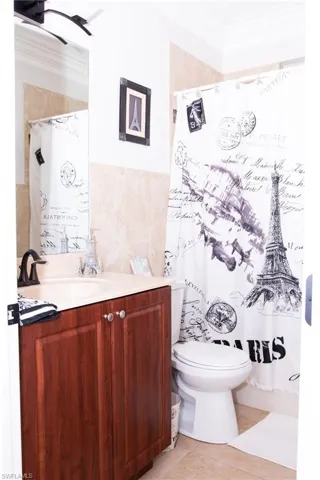 Bathroom featuring vanity, tile patterned floors, crown molding, toilet, and tile walls