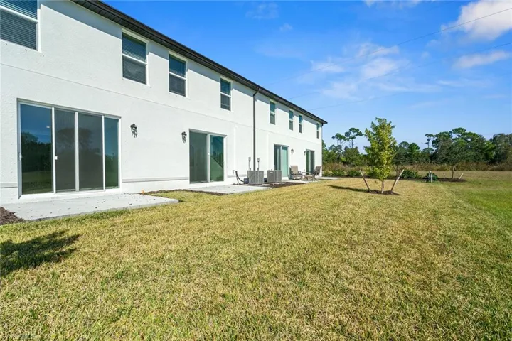 Back of house featuring a patio, a yard, and stucco siding