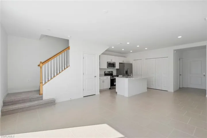 Kitchen featuring a center island with sink, white cabinets, open floor plan, stainless steel appliances, and recessed lighting