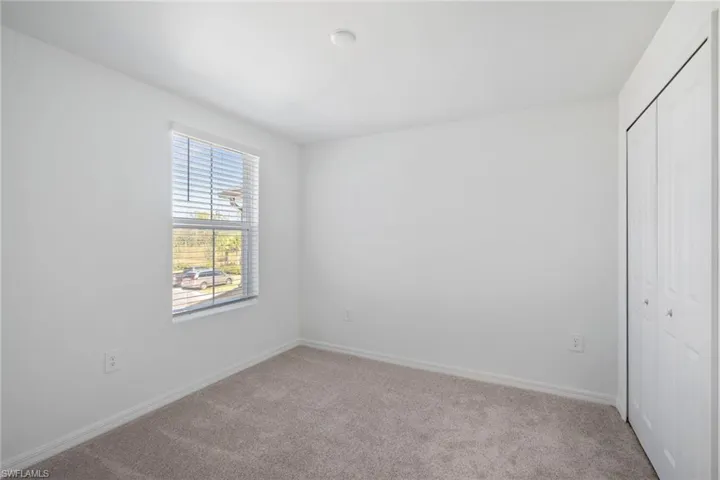Unfurnished bedroom featuring light carpet and a closet