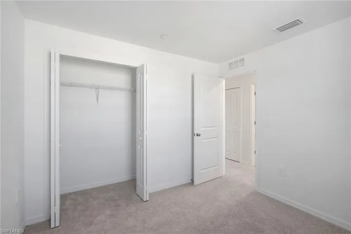 Unfurnished bedroom with light colored carpet and a closet