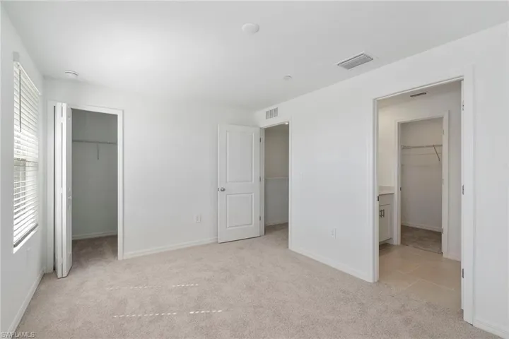 Unfurnished bedroom with a walk in closet and light colored carpet