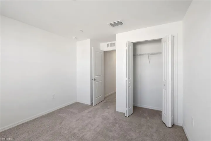 Unfurnished bedroom featuring light carpet and a closet