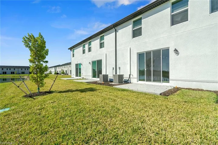 Back of house with stucco siding, a yard, and a patio area