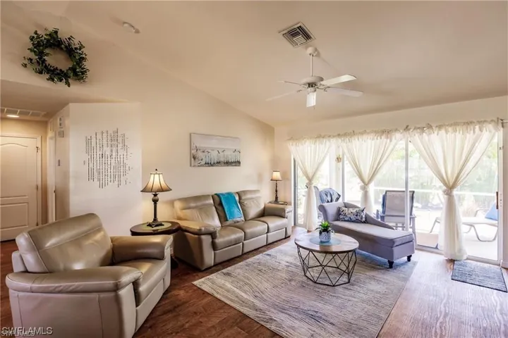 Living area with lofted ceiling, wood finished floors, and ceiling fan