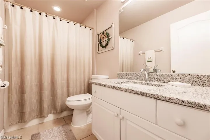 Bathroom featuring vanity, light tile patterned floors, and a shower with curtain