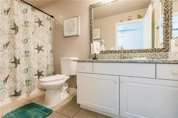 Full bathroom with light tile patterned floors, vanity, and a shower with shower curtain
